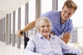 Nurse Pushing Senior Patient In Wheelchair Along Corridor Royalty Free Stock Photo