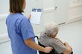 Nurse pushing senior patient in a wheelchair, reading medical document in clipboard. Emotional support for elderly woman Royalty Free Stock Photo