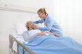 Nurse puts oxygen mask on elderly woman patient lying in the hospital room bed, coronavirus covid 19 protection concept.