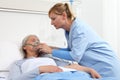 Nurse puts oxygen mask on elderly woman patient lying in the hospital room bed Royalty Free Stock Photo