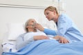 Nurse puts oxygen mask on elderly woman patient lying in the hospital room bed Royalty Free Stock Photo