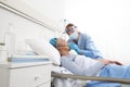 Nurse puts oxygen mask on elderly woman patient lying in the hospital room bed, wearing protective gloves and visor medical mask,