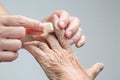 Nurse putting adhesive bandage on elderly hand