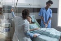 Nurse putting pulse oximeter on patient finger while doctor setting up central line catether