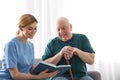 Nurse reading book to elderly man. Assisting senior people Royalty Free Stock Photo