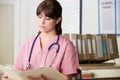 Nurse Reading Patient Notes At Nurses Station Royalty Free Stock Photo