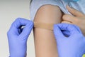 Nurse in rubber protective gloves putting bandage plaster on teenager arm after vaccination. Injection covid vaccine Royalty Free Stock Photo