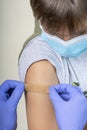 Nurse in rubber protective gloves putting bandage plaster on teenage boy arm after vaccination. Injection covid vaccine Royalty Free Stock Photo