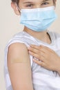 Nurse in rubber protective gloves putting bandage plaster on teenage boy arm after vaccination. Injection covid vaccine Royalty Free Stock Photo