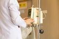 Nurse`s hand operating IV machine in patient room