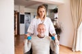 Nurse and senior man in wheelchair during home visit. Royalty Free Stock Photo