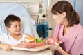 Nurse Serving Child Patient Meal In Hospital Bed