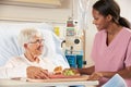 Nurse Serving Senior Female Patient Meal In Hospital Bed