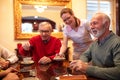 Nurse serving tea while older people play board games, retirement home