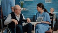 Nurse showing osteopathy x ray on tablet to disabled old man Royalty Free Stock Photo