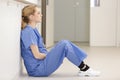 nurse sitting alone on floor in hospital corridor Royalty Free Stock Photo