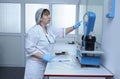 Nurse standing in front of a table with scale holding containers with blood for weighing Royalty Free Stock Photo