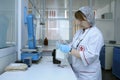 Nurse standing in front of a table with scale holding containers with blood for weighing. Lab of the City municipal blood