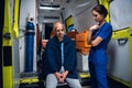 Nurse standing beside a patient who is sitting on the edge of an ambulance car Royalty Free Stock Photo