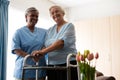 Nurse standing by senior woman holding walker in nursing home Royalty Free Stock Photo