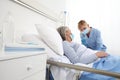 Nurse with the syringe injects the vaccine to the elderly woman patient lying in the hospital room bed, wearing protective gloves Royalty Free Stock Photo