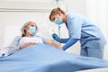 Nurse with the syringe injects the vaccine to the elderly woman patient lying in the hospital room bed, wearing protective gloves Royalty Free Stock Photo