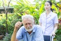 Nurse take care a depressed thoughtful senior retirement man on his wheelchair in a garden in his home Royalty Free Stock Photo