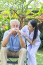 Nurse take care a depressed thoughtful senior retirement man on his wheelchair in a garden in his home Royalty Free Stock Photo