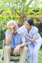 Nurse take care a depressed thoughtful senior retirement man on his wheelchair in a garden in his home Royalty Free Stock Photo