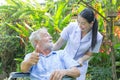 A nurse take care a senior male on wheelchair in his garden at home Royalty Free Stock Photo