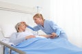 Nurse take comfort elderly woman lying in the hospital room bed, by stroking her and holding the arm where the drip needle is, Royalty Free Stock Photo