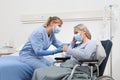 Nurse take comfort elderly woman in wheelchair wearing surgical protective medical masks in hospital room, concept of isolation