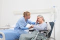 Nurse take comfort sad and pensive elderly woman isolated on wheelchair near bed in hospital room, concept of loneliness and old