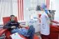 Nurse taking blood from the vain of the donor, hypodermic needle, tubes, container with blood