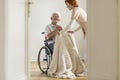 Nurse taking care of happy elderly man in a wheelchair in his ho