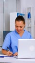 Nurse taking notes on clipboard after reading medical raports from laptop Royalty Free Stock Photo