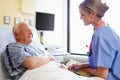 Nurse Talking To Senior Male Patient In Hospital Room