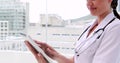 Nurse in tunic using tablet pc and smiling at camera