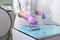 A nurse in a uniform and medical mask lays out sterile dental instruments Packed in a Kraft bag. Unrecognizable photo.Gloved hand