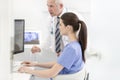 Nurse using laptop at desk while senior doctor explaining in clinic Royalty Free Stock Photo