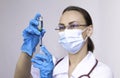 A nurse wearing protective gloves and a mask dials a vaccine into a syringe, the concept of vaccinating the population Royalty Free Stock Photo