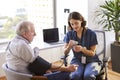 Nurse Wearing Scrubs In Office Checking Senior Male Patients Blood Pressure Royalty Free Stock Photo