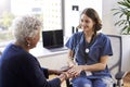 Nurse Wearing Scrubs In Office Reassuring Senior Female Patient And Holding Her Hands Royalty Free Stock Photo