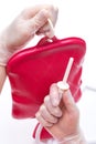 Nurse wearing sterile rubber gloves holds Cleansing Enema Bucket Set on white background. Enema Mug