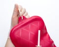 Nurse wearing sterile rubber gloves holds Cleansing Enema Bucket Set on white background. Enema Mug