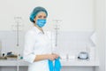 A nurse in a white coat puts on gloves before a medical procedure in a bright handling room Royalty Free Stock Photo