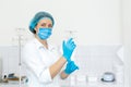 A nurse in a white coat puts on rubber gloves before a medical procedure in a bright handling room Royalty Free Stock Photo