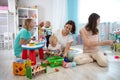 Nursery babies play together with moms in creche or children club