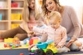 Nursery babies playing with adults in day care center Royalty Free Stock Photo