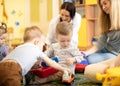 Nursery babies playing together with moms in a play room Royalty Free Stock Photo